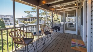 A covered porch with wicker chairs, a glass table, and a view of neighboring houses. - Newly Updated OCEAN BLOCK 2 bedroom condo, steps away from the beach! (Dewey Beach)