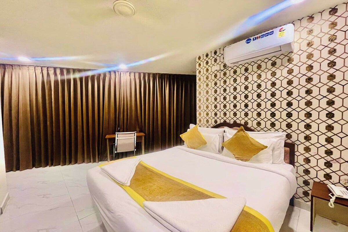 Ein Hotelzimmer mit einem großen Bett, einem Nachttisch mit Telefon und einer Wand-Klimaanlage.