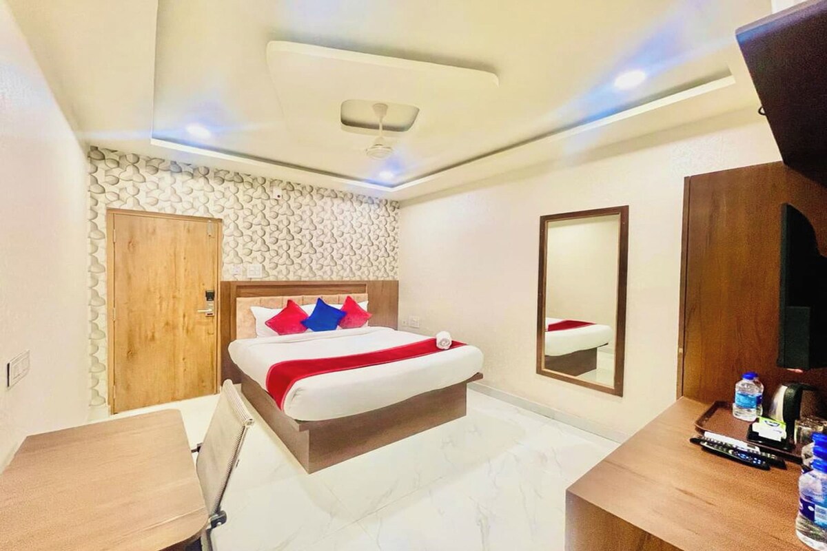 Una habitación de hotel con cama, escritorio, espejo y armario.