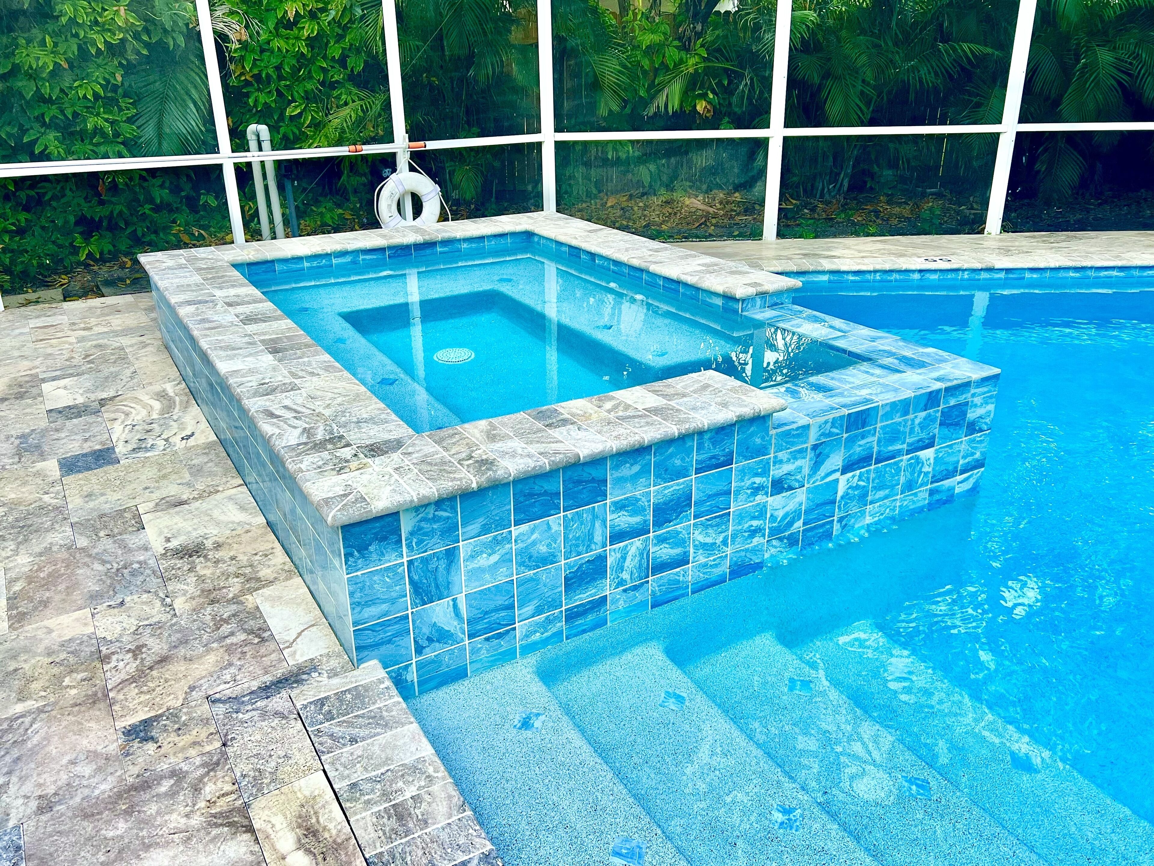 A rectangular hot tub with a clear blue interior, surrounded by a tiled deck.