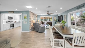 A modern kitchen with white cabinets, a dining area with a wooden table and chairs, and a large window with a view of greenery. - 7 minute walk to Siesta Key beach.  Large heated pool/spa. Very private.1/2 acre (Siesta Key)