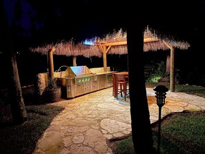 An outdoor bar area with a grill, seating, and a thatched roof structure. - 7 minute walk to Siesta Key beach.  Large heated pool/spa. Very private.1/2 acre (Siesta Key)