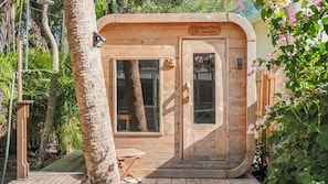 A wooden cabin with a door and window, surrounded by greenery. - 7 minute walk to Siesta Key beach.  Large heated pool/spa. Very private.1/2 acre (Siesta Key)