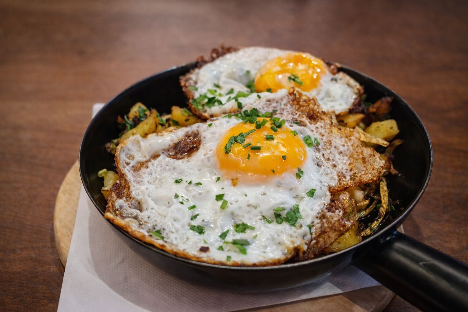 A skillet with two sunny-side-up eggs and sautéed potatoes.