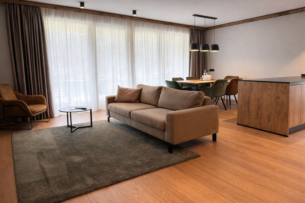 Un salon moderne comprenant un canapé, une table basse, un coin repas avec des chaises et un comptoir de cuisine.