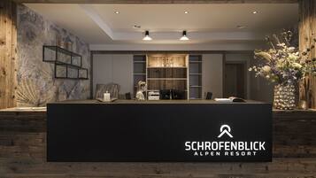Ein Empfangsbereich im Schorenblick Alpen Resort mit modernem Design, Holzelementen und einer großen Blumenkomposition.