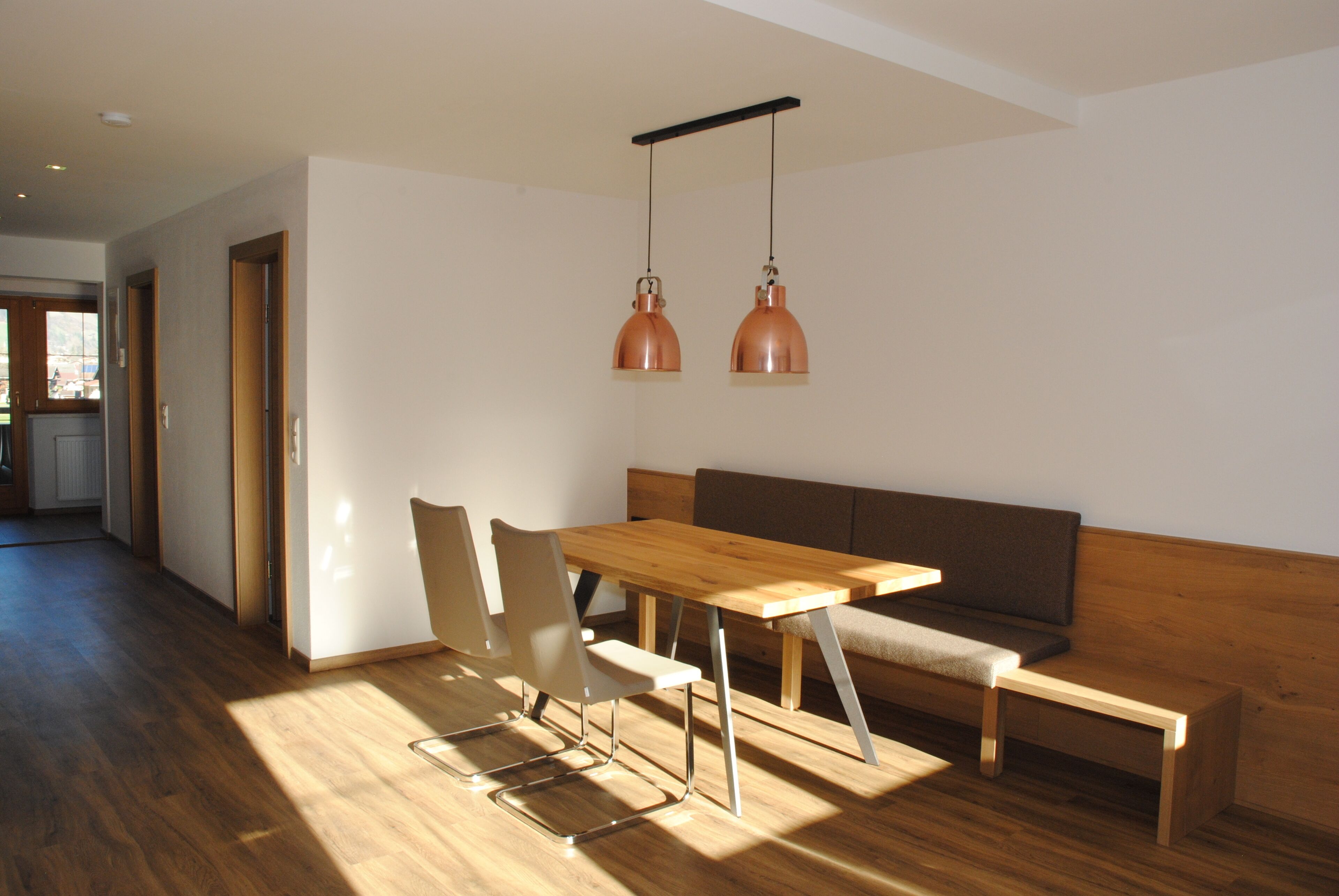 A modern dining area with a wooden table, chairs, and a bench.