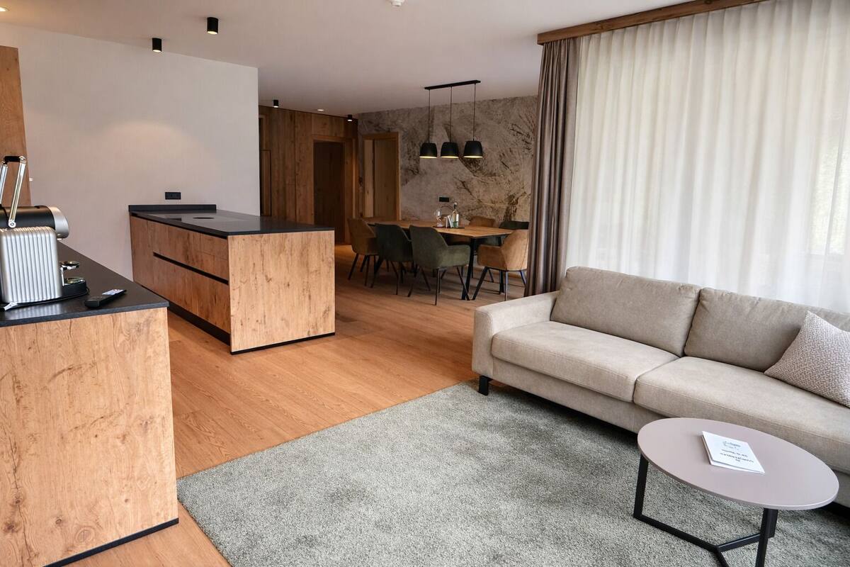 Un salon moderne comprenant un canapé, une petite table ronde et un coin cuisine avec un comptoir en bois et une table à manger.