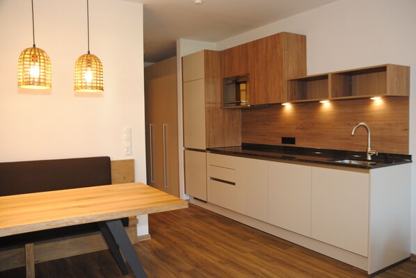 A modern kitchen with wooden cabinets, a built-in oven, and a stainless steel sink. - Resort Schrofenblick (Schwendau)