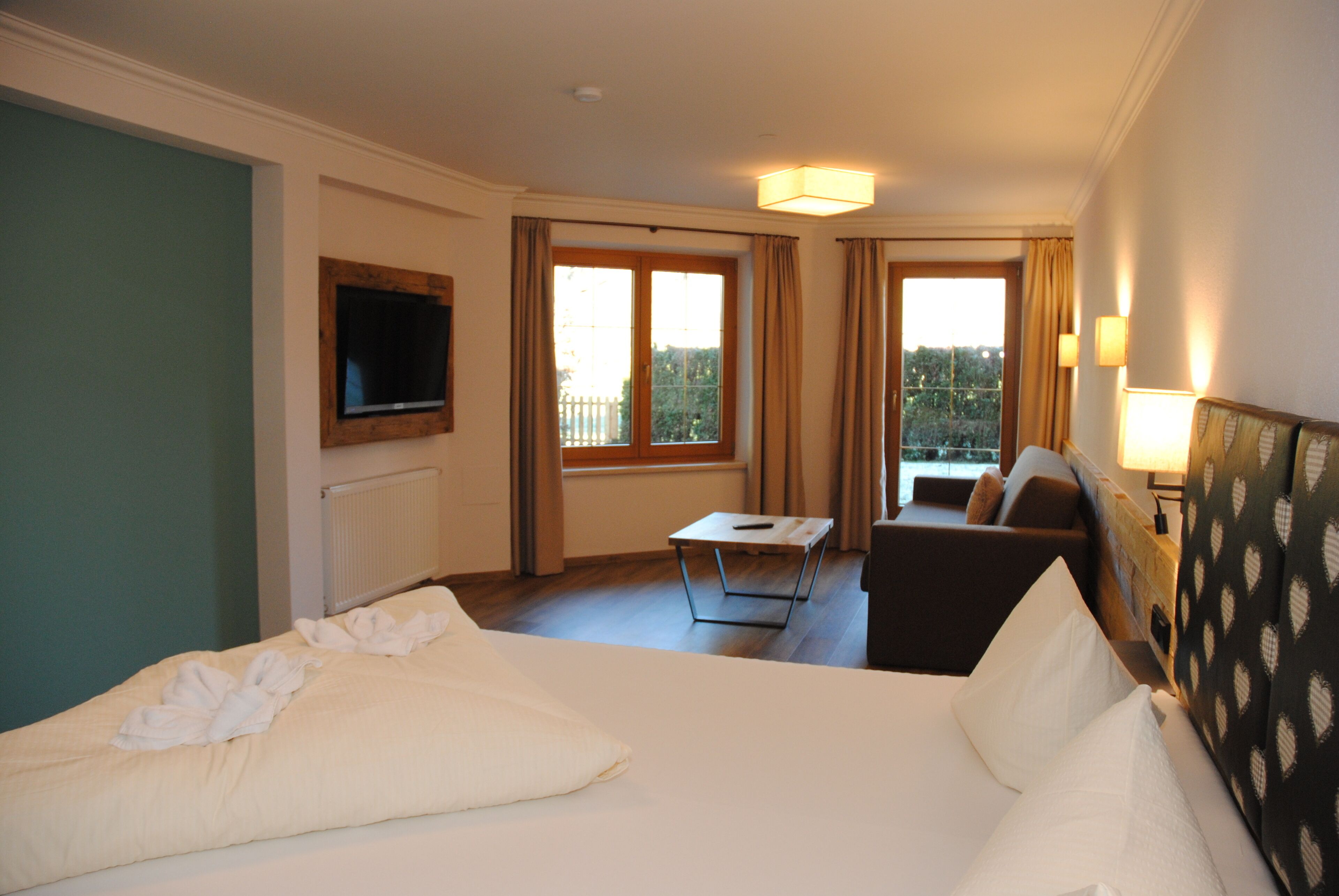 Habitación de hotel con una cama grande, un sofá, una mesita y un televisor en la pared.