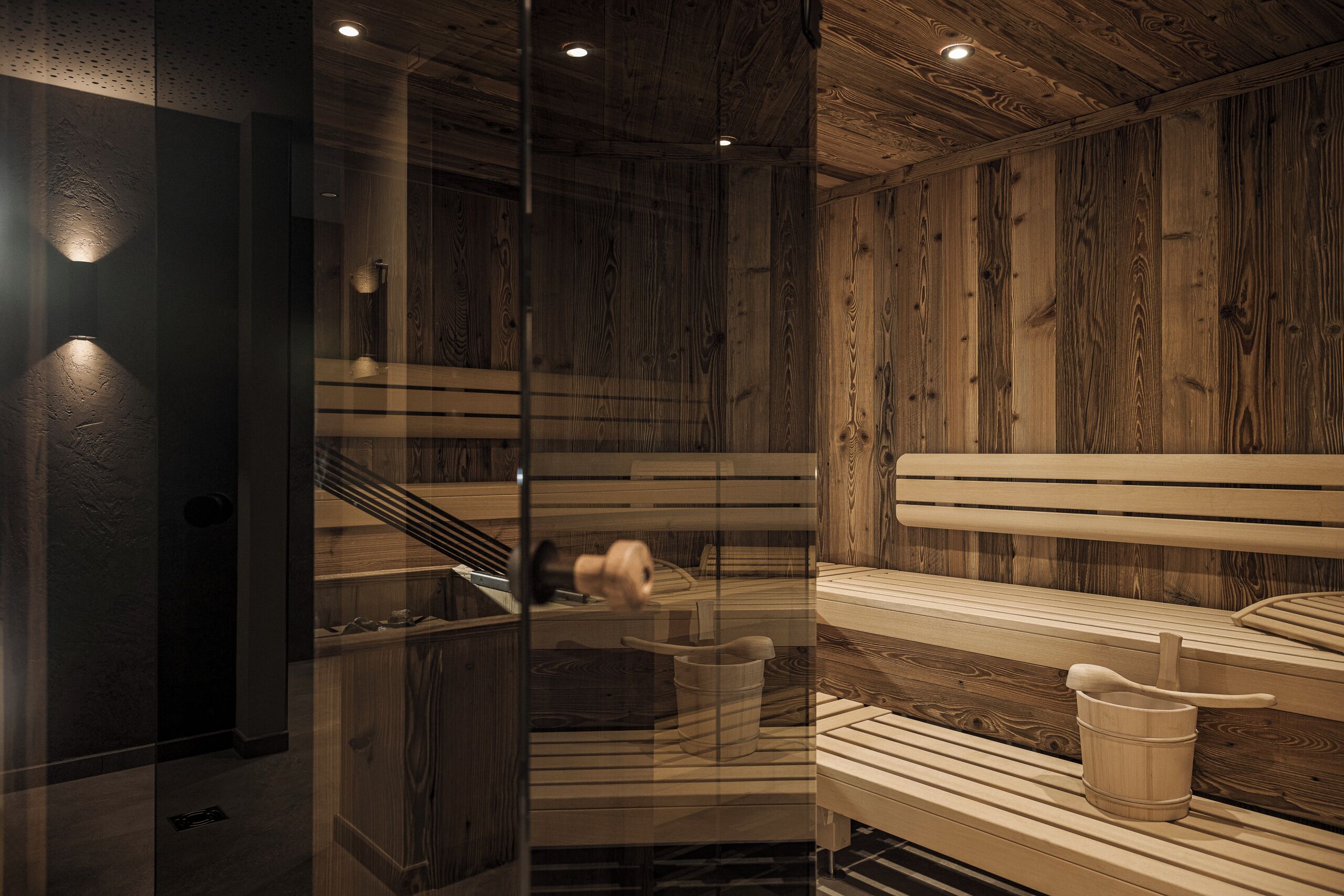 A sauna with wooden benches and a glass partition.