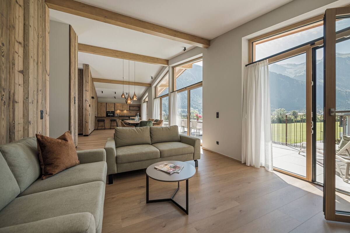 Un vaste espace de vie comprenant un canapé, une table basse et une vue imprenable sur un paysage montagneux grâce à de grandes fenêtres.
