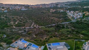 Vista aérea de una zona residencial con casas modernas, una piscina grande y una calle.