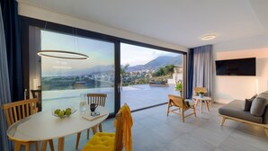 Una sala de estar moderna con un gran ventanal que da a un balcón, un comedor con mesa y sillas, y un sofá.