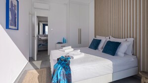 Una habitación de hotel moderna con una cama grande, un baño con lavabo y un panel de pared de madera.