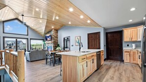 A spacious kitchen with wooden cabinets, a large island, and a view of the outdoors.