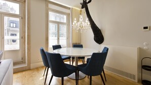 Un coin repas comprenant une table ronde, six chaises, un lustre et une sculpture de girafe accrochée au mur.