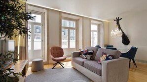 Un salon moderne avec un canapé, des fauteuils, un lustre et une décoration représentant une girafe.