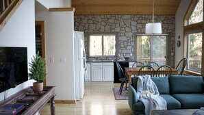 A spacious living area with a stone wall, wooden ceiling, and large windows.