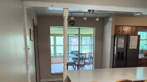 A kitchen with a large island, wooden chairs, and a view of the outdoors.