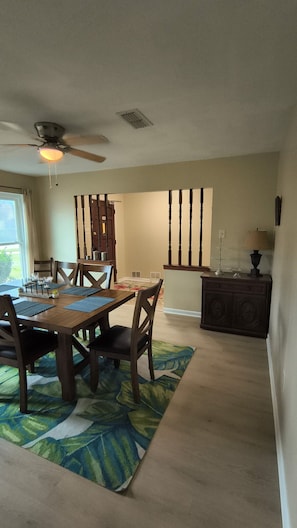 A dining area with a wooden table, chairs, and a ceiling fan.