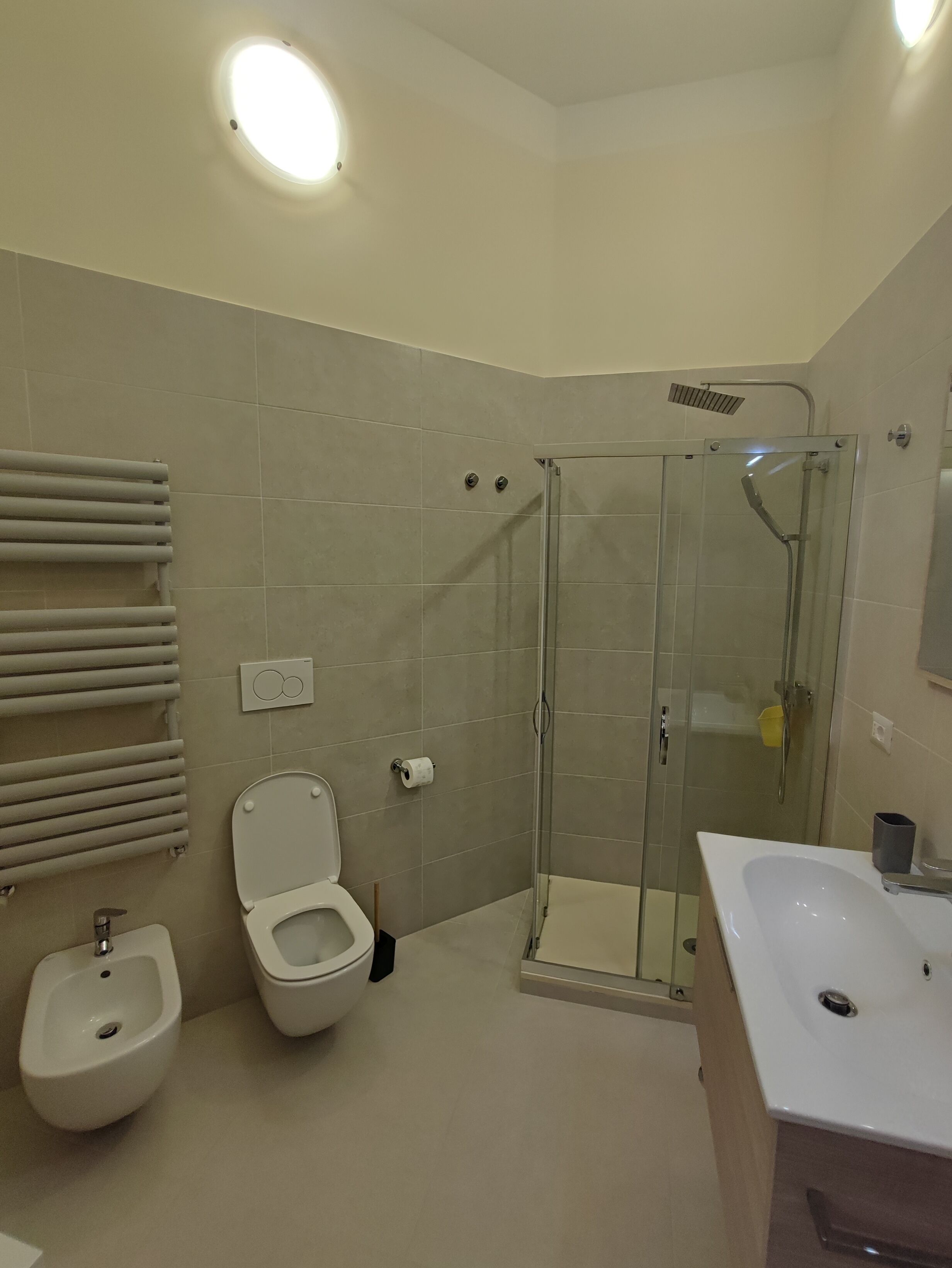 Une salle de bain moderne dotée d’une douche à parois de verre, d’un bidet, de toilettes et d’un lavabo.