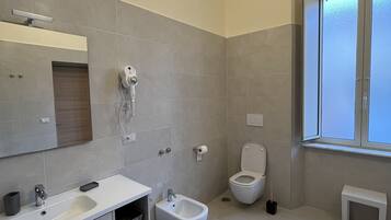 Un bagno moderno con lavandino, bidet, WC e una piccola panca.