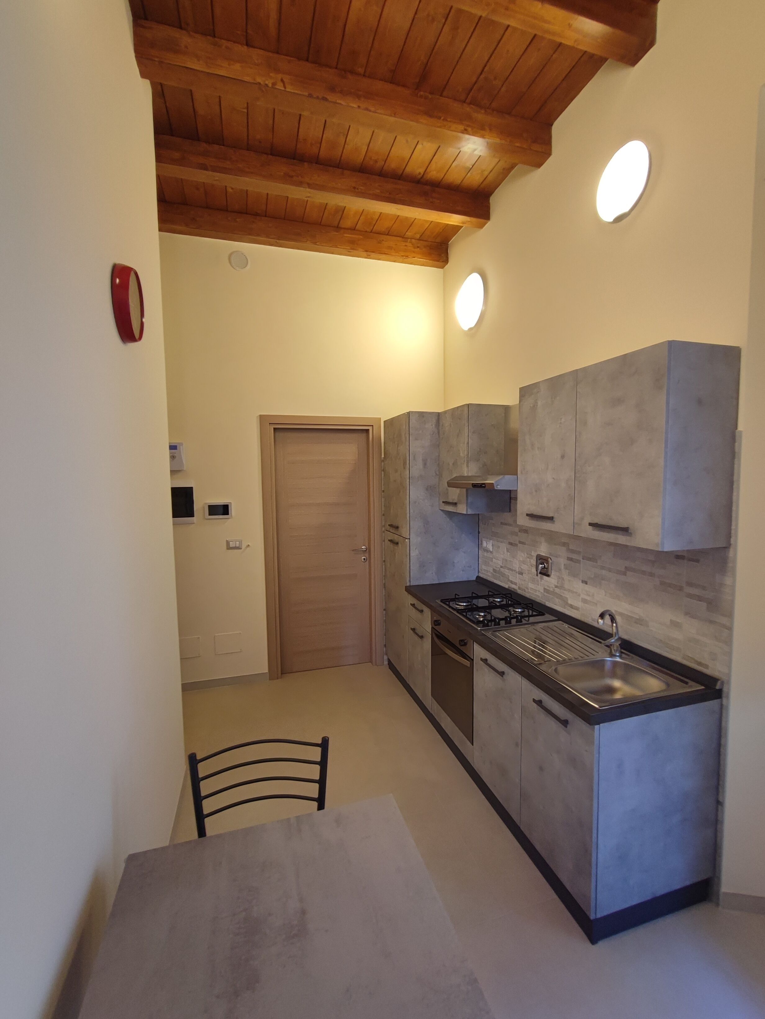 Une cuisine de taille réduite avec un plafond en bois, une cuisinière à gaz, un évier et des placards.