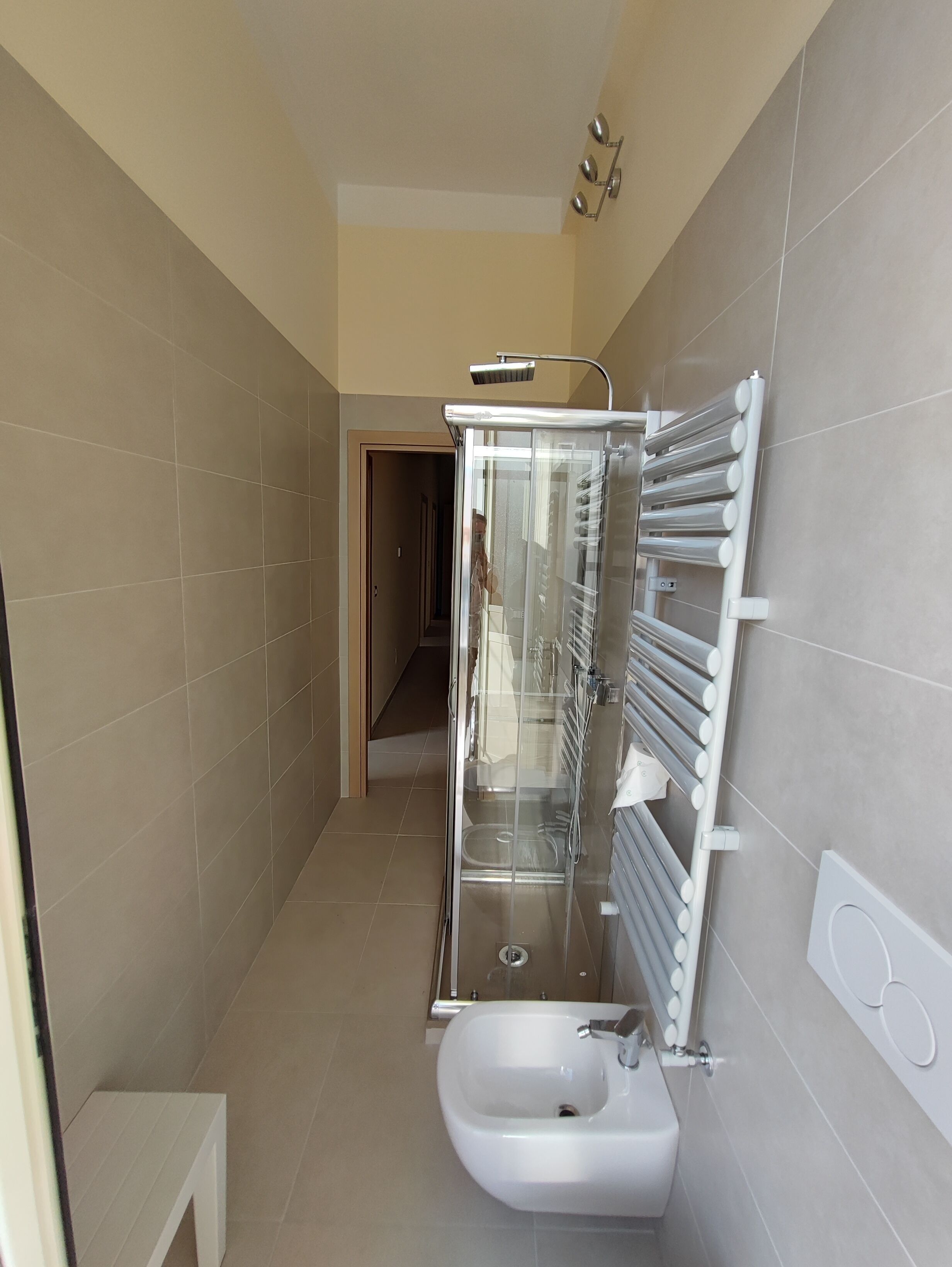 Un baño moderno con ducha de vidrio, lavabo blanco y barra para toallas.