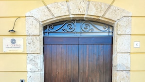 A large wooden door with a stone archway, a sign for 'In Centro Rooms and Apartments', and a small mailbox on the left. - In Centro - Rooms and Apartments  (Isola del Liri)