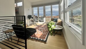 A spacious balcony with a city view, a comfortable seating area, and a small table with a plant. - Live/Work House w/Views, Yard, Parking 3br/2ba (San Francisco)