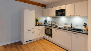 Una cocina moderna con armarios blancos, horno empotrado, microondas y fregadero.