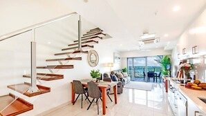 A modern interior with a staircase, dining area, and kitchen. - Zen Sea View 2BR, 2BA Penthouse (Darwin City)