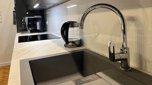 A modern kitchen with a sleek black and white color scheme, featuring a built-in coffee machine and a stainless steel faucet.