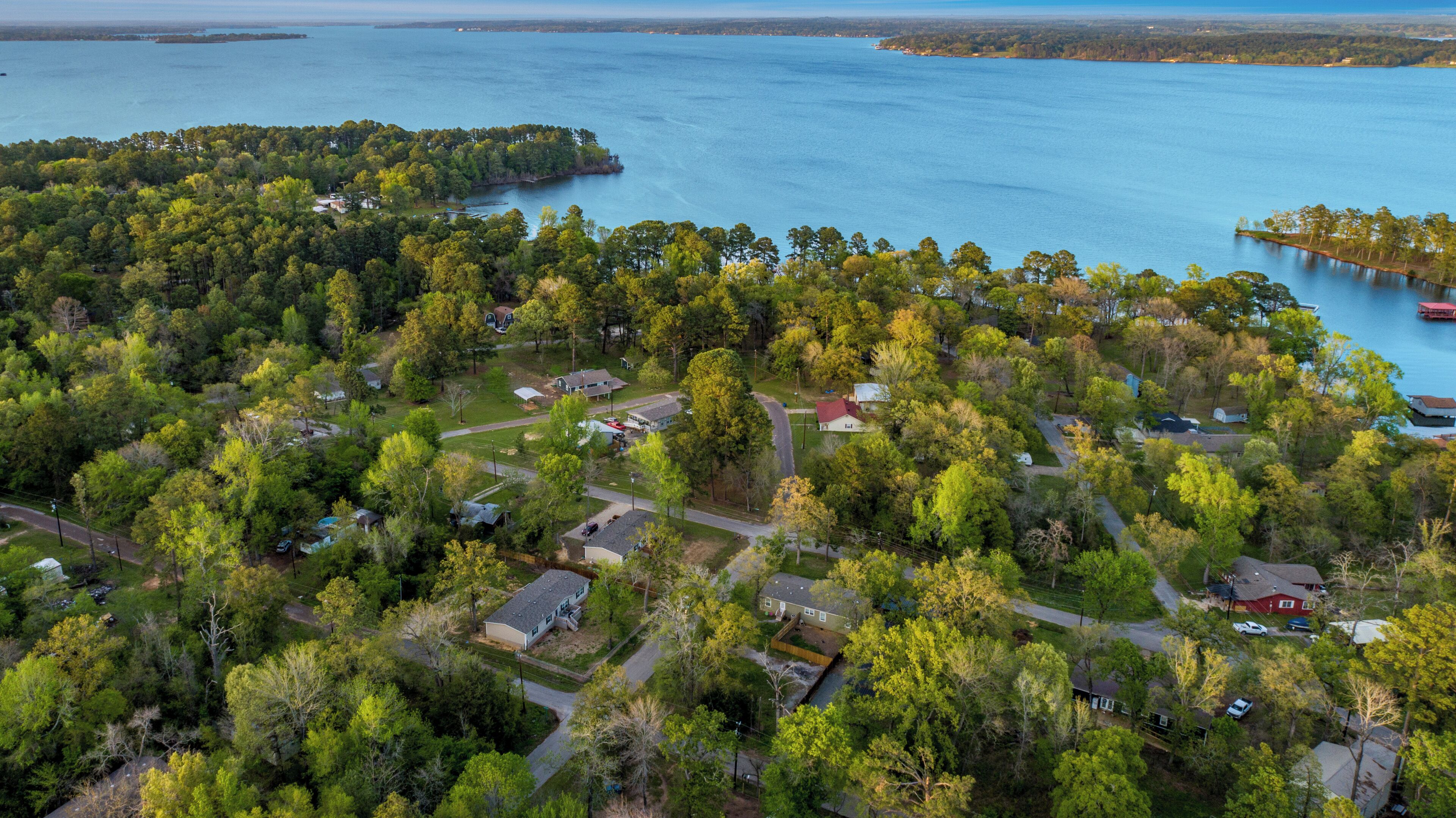 An aerial view of a residential area with houses, roads, and a body of water.