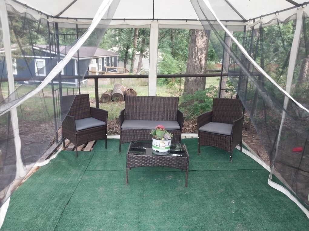 A covered patio area with wicker furniture and a table, surrounded by a mesh enclosure.