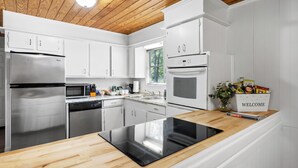 Una cocina moderna con armarios blancos, electrodomésticos de acero inoxidable y encimera de madera.