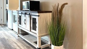 Een gang met een houten kast, een magnetron en een potplant.