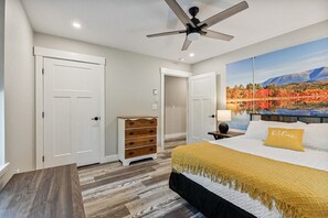 A bedroom with a bed, a nightstand, a dresser, a ceiling fan, and a painting of a landscape. - Cozy | 3 BR/2 Bath | Sleeps 8 | Quiet (Brewer)
