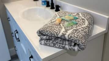 Un baño con un lavamanos blanco, un espejo y una toalla sobre el mostrador.