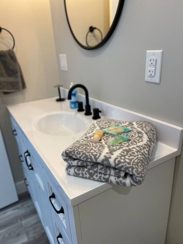 A bathroom with a white sink, a mirror, and a towel on the counter.