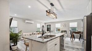 Una cocina moderna con una isla central, muebles blancos y un comedor con mesa y sillas.