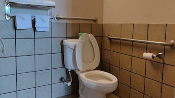Une petite salle de bain propre, équipée de toilettes, d’un sèche-mains et d’un porte-serviettes.