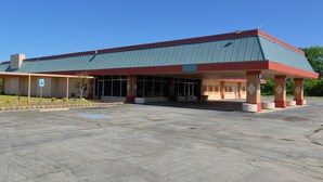 A building with a covered entrance, large windows, and a parking lot. - Countryside Inn & Suites (Idabel)