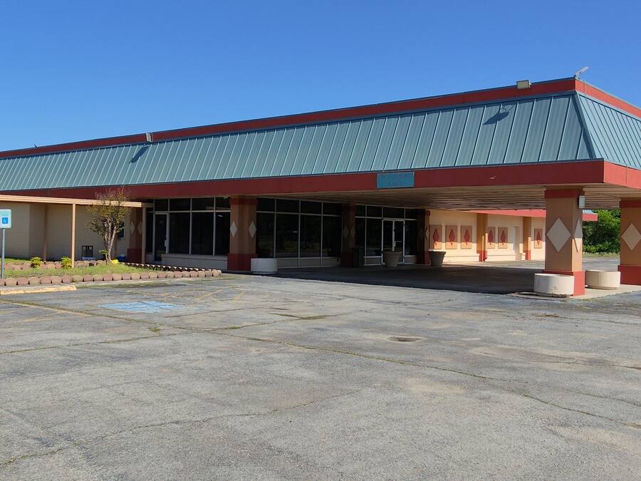 A building with a covered entrance, large windows, and a parking lot.