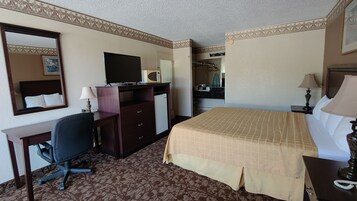 Una habitación de hotel con cama, escritorio, silla, cómoda y televisor.