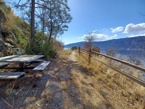 Ein Picknickplatz mit Bänken und einem Holzzaun mit Blick auf einen See und Berge.