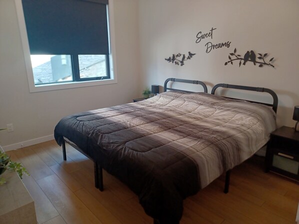 A bedroom with a bed, a window, a wall decoration, and a nightstand. - Beautiful 2 bed 2 bath with incredible lake view!! (Lake Country)