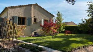 A house with a sloped roof, a visible chimney, and a well-maintained lawn with a few trees. - House with garden in Provence (Valréas)