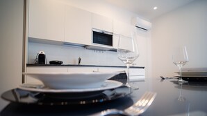 Une cuisine moderne avec des meubles blancs, un four à micro-ondes et une table à manger dressée avec des assiettes, des verres et des couverts.